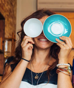 Sarah, holding up a cup and saucer in place of her eyes